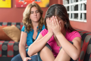 Sad teenage girl cries next to her worried mother