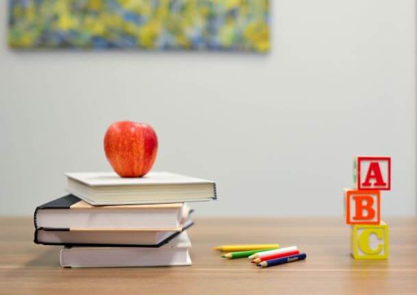 apple, books, and blocks on teachers desk