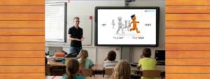 Teacher with a screen beside him displaying a lesson from Lexercise in a classroom