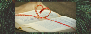 image of book with a heart shaped bow and a christmas tree behind