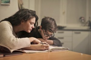 woman sitting at table helping child with dyslexia at home with reading