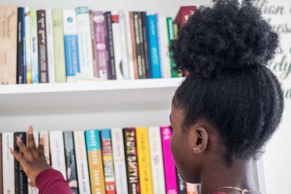 Young girl chooses a book from a bookshelf