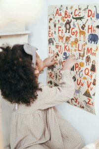 Young girl looks at a poster with an illustrated alphabet 